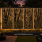 A decorative outdoor wall panel set with a black bamboo leaf pattern, illuminated from within to show a warm golden glow against a wooden fence in a backyard setting.